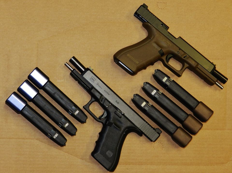 Two Glock pistols with magazines laid out on a wooden surface