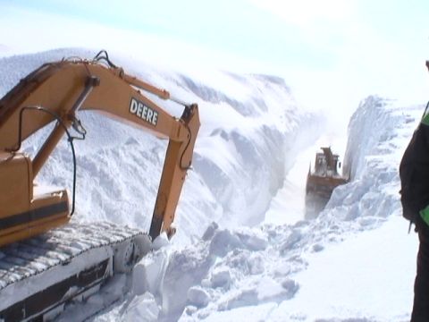 1979 Ford Bronco - Heavy machinery works to clear a snow-covered path, with an excavator in the foreground and a bulldozer in the distance.