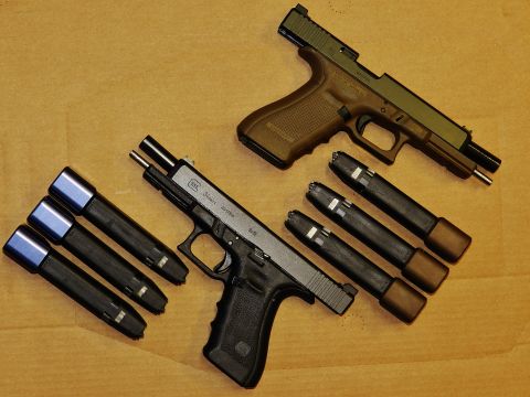 1996 Ford Bronco - Two Glock handguns and multiple magazines are laid out on a wooden surface, with text indicating 'Supermotors.net'.