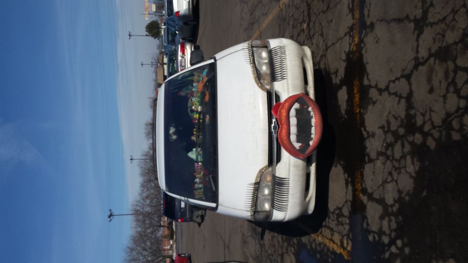 White SUV with novelty teeth grille and eyelashes, parked in a lot