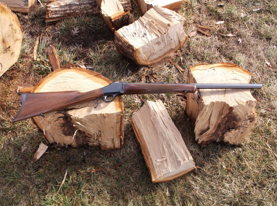Rifle with wooden stock and metal barrel resting on cut logs