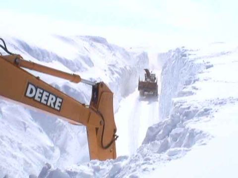 1979 Ford Bronco - Heavy machinery operates in a snow-covered landscape, with a snow blower carving a path through deep snow.