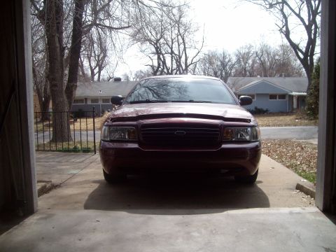2004 Ford Crown Victoria - A maroon Ford Crown Victoria is parked head-on in a garage, with its hood slightly open.