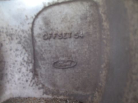 2004 Ford Crown Victoria - Cast metal part with Ford logo and embossed numbers '077521 64'.