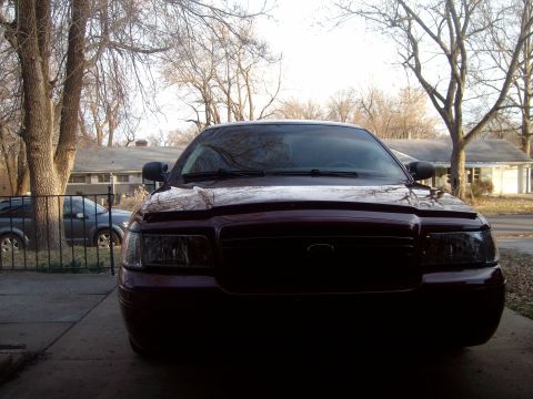 2004 Ford Crown Victoria - A dark red 2004 Ford Crown Victoria is parked in a driveway, with another vehicle visible in the background.
