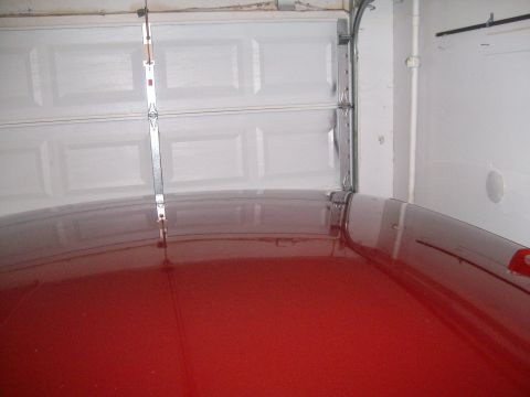 2004 Ford Crown Victoria - A bright red car roof is visible beneath a partially open white garage door. The image includes a watermark for SUPERMOTORS.NET.
