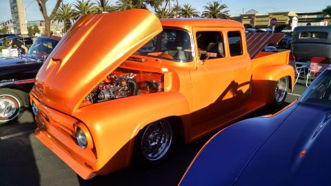 1979 Ford Bronco - Custom orange pickup truck displayed with its hood open at a car show.