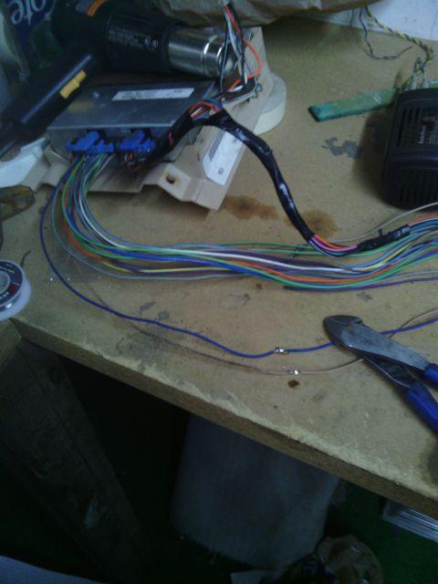 1978 Ford Bronco - An automotive wiring harness and electronic control unit are laid out on a workbench, ready for modification.