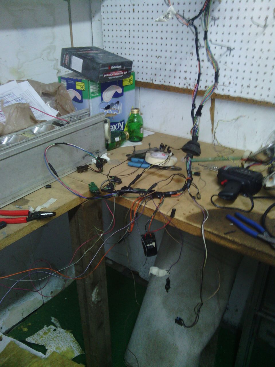 Vehicle wiring harness spread out on a workbench with tools