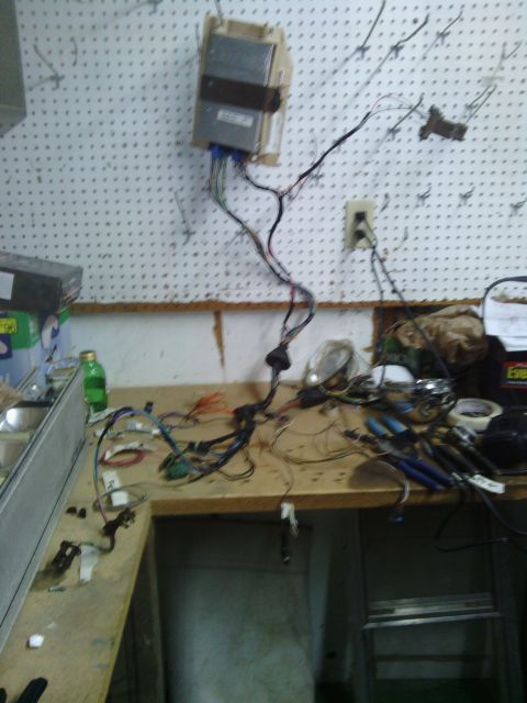 1978 Ford Bronco - A messy automotive wiring harness and control module are spread out on a workbench.
