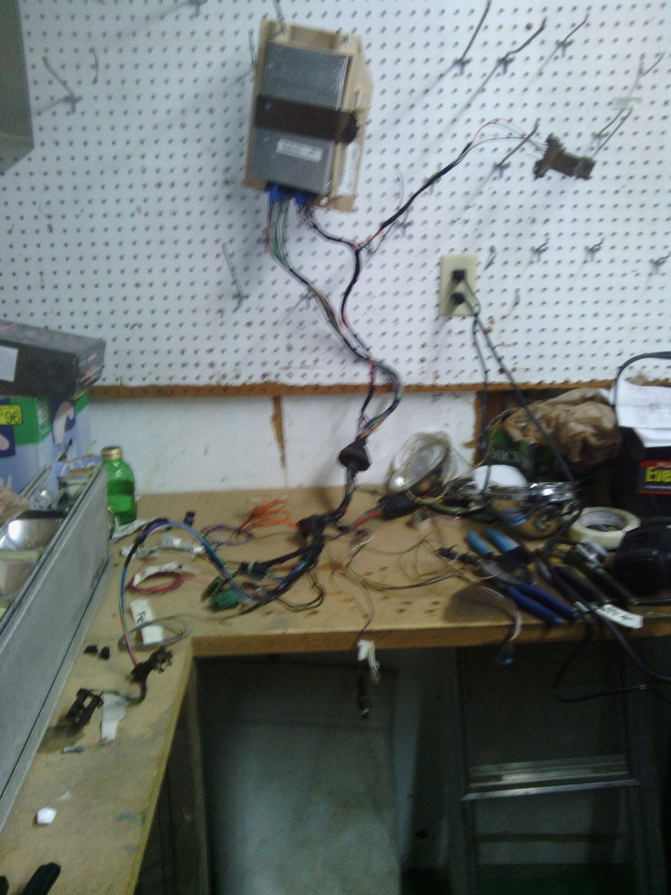 Automotive wiring harness and control module on a workbench with tools
