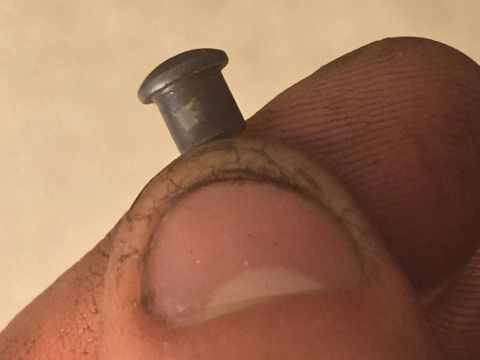 2014 Dodge 1500 - A small metal pin is held on a thumb, showing its detail.
