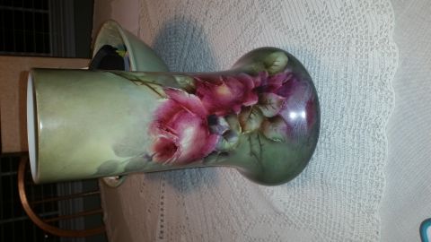 2015 Chevrolet new - A decorative vase painted pink roses on a green, speckled background, placed on a lace tablecloth.
