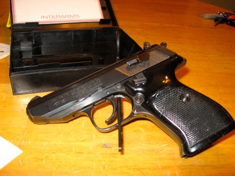 1976 Dodge Power Ram - A black Interarms Walther PPK pistol rests on a wooden surface next to its open black case.