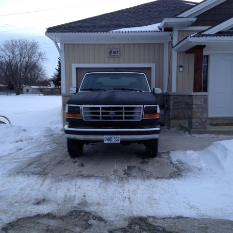 1992 Ford Bronco - A black 1992 Ford Bronco is parked in a driveway covered in snow, facing the camera.