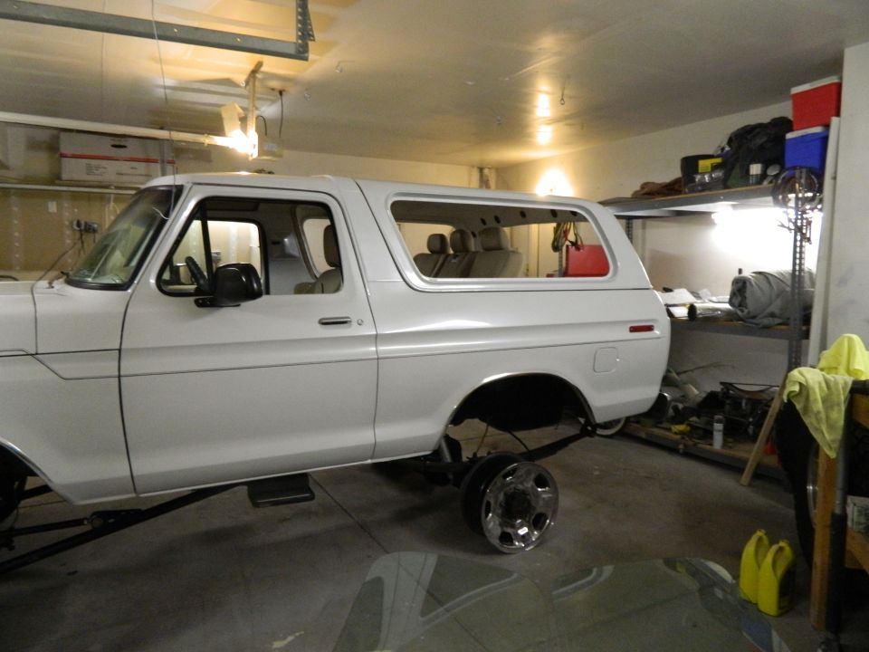 White Ford Bronco, likely 1978 model, in a garage with rear axle removed