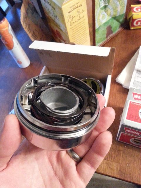 1981 Ford Bronco - A chrome Warn Hub assembly with internal components is held in a hand, with boxes in the background.
