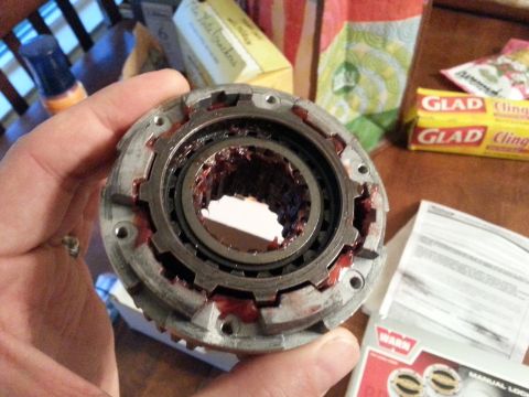 1981 Ford Bronco - Close-up of a Warn locking hub part, held by a hand. A "WARN" logo is visible on a document in the background.