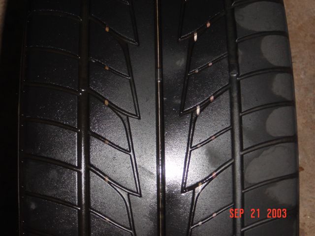 Close-up of a black tire tread with visible wear and small orange specks