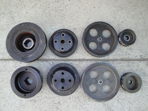 1995 Ford Taurus - Several automotive pulleys are laid out on a gray concrete surface.