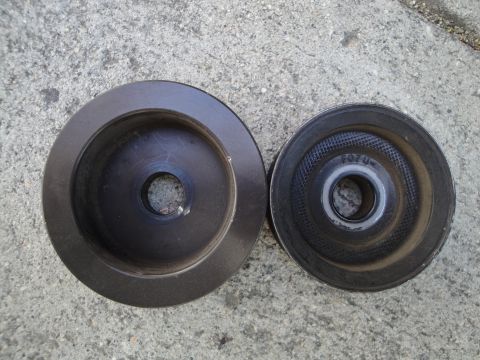 1995 Ford Taurus - Two automotive pulleys shown on a concrete surface. One has visible text and a bearing.