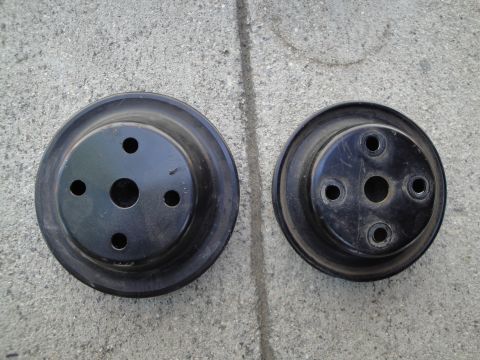 1995 Ford Taurus - Two black automotive pulleys are shown on a concrete surface, with visible mounting holes.