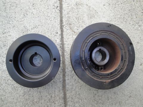 1995 Ford Taurus - Two crankshaft pulleys are shown, one black and one dark metal, both a central keyway for installation.