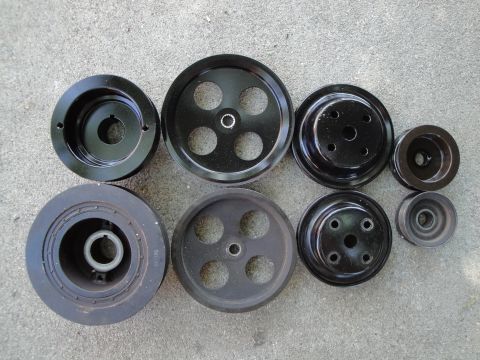 1995 Ford Taurus - A collection of assorted automotive pulleys are displayed on a textured gray surface.
