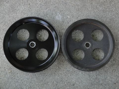 1995 Ford Taurus - A comparison of a new drive pulley next to a used one, both with four circular cutouts and a central splined hub.