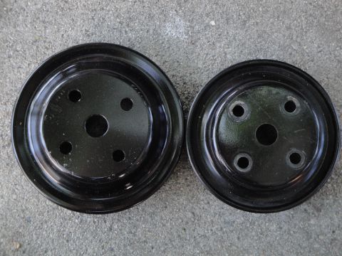 1995 Ford Taurus - Two black pulleys, likely for an engine's drive system, are shown on a concrete surface.