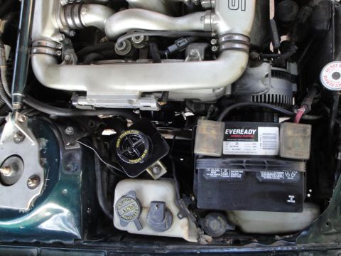 1995 Ford Taurus - Close-up view of engine components including the battery and power steering fluid reservoir.