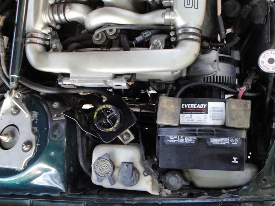Engine bay with battery, power steering fluid reservoir, and intake manifold visible