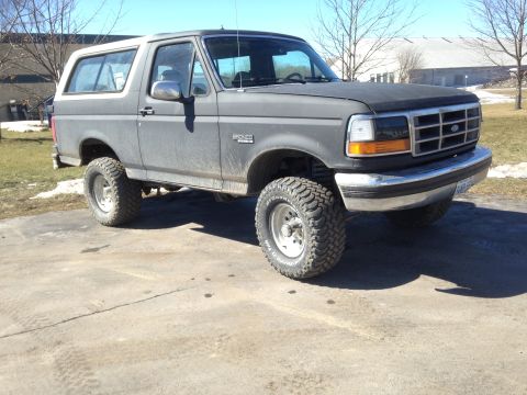 1992 Ford Bronco - This 1992 Ford Bronco is shown from a three-quarter front angle, highlighting its lifted suspension and off-road tires.