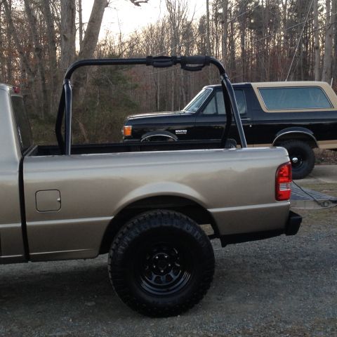 1991 Ford Bronco - A black 1991 Ford Bronco is parked behind a tan pickup truck.