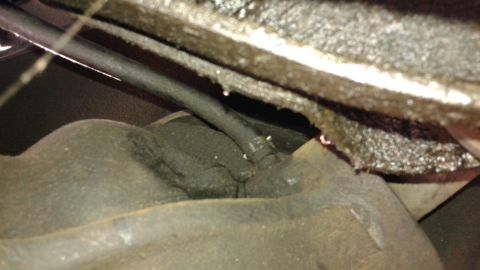 1988 Ford Bronco - Undercarriage view of greasy mechanical components, including hoses and metal structures.