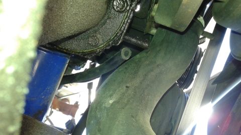 1988 Ford Bronco - Close-up view of engine components including hoses and belts, with some oil residue visible.
