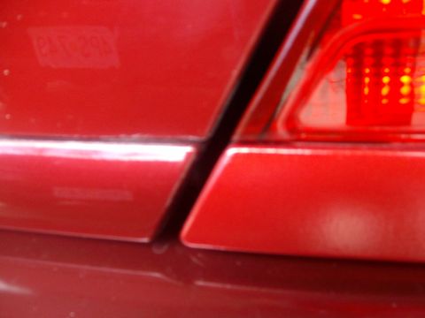 2004 Ford Crown Victoria - Close-up of the rear tail light and body panel gap on a red 2004 Ford Crown Victoria.
