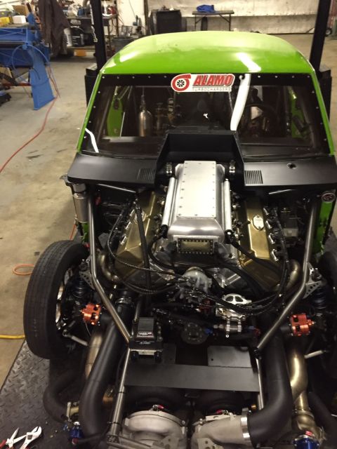 1965 Ford Fairlane - The custom engine bay of a drag racing car is shown with extensive modifications and exposed components.