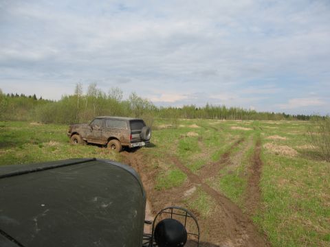 1987 Ford Bronco - Muddy 1987 Ford Bronco navigating off-road terrain with another vehicle visible in the foreground.
