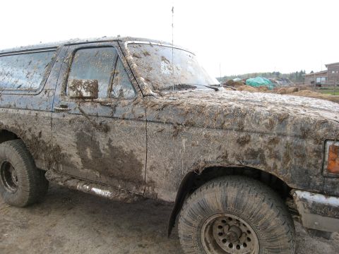 1987 Ford Bronco - This 1987 Ford Bronco is heavily covered in mud and debris, suggesting it has been used off-road.