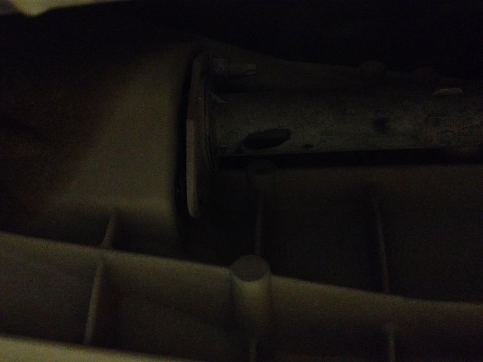 Close-up of a dark, possibly metal, vehicle part with some texture and a cylindrical protrusion