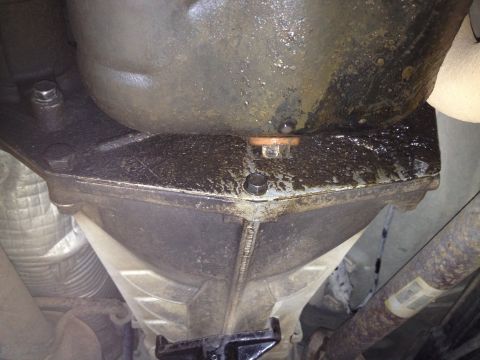 2005 Jeep Wrangler - Underside view of a transmission pan showing an oil leak around the drain plug.
