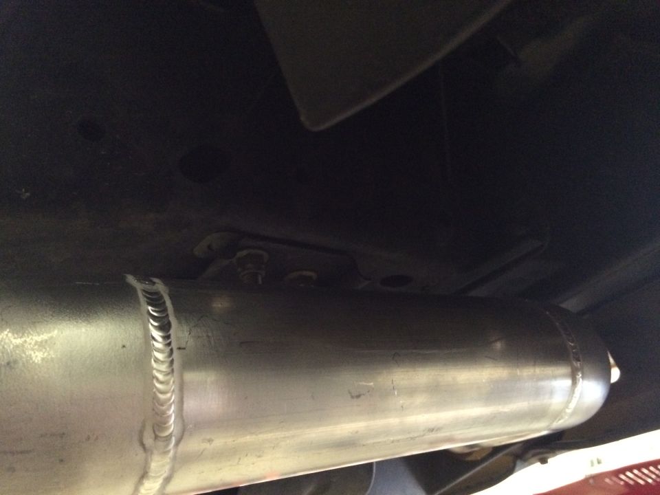 Underside view of a vehicle's exhaust pipe with visible weld marks
