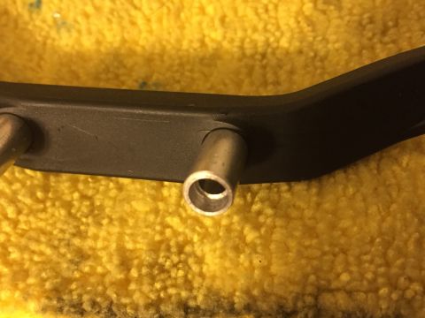 2014 Dodge 1500 - A close-up view of a black metal bracket with silver posts, resting on a yellow textured surface.