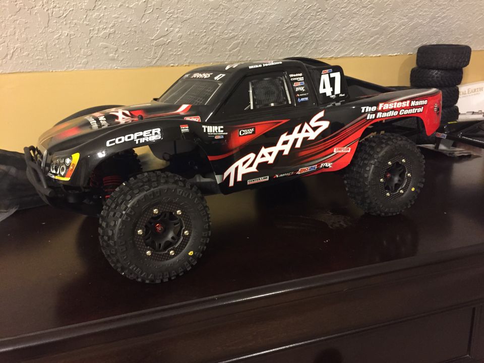 Black Traxxas remote control short course truck with red graphics and number 47