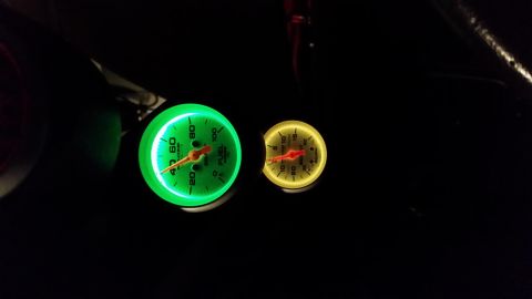 2004 Mercury Grand Marquis - Illuminated fuel level and another gauge glow green and yellow in the dark interior of a vehicle.
