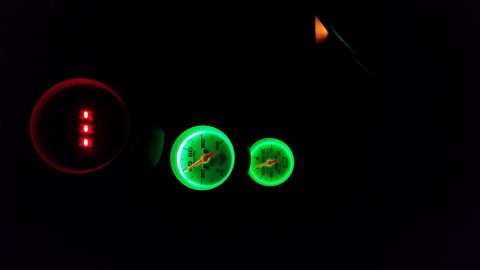 2004 Mercury Grand Marquis - Interior view of illuminated dashboard gauges with red indicator lights and two green dials.