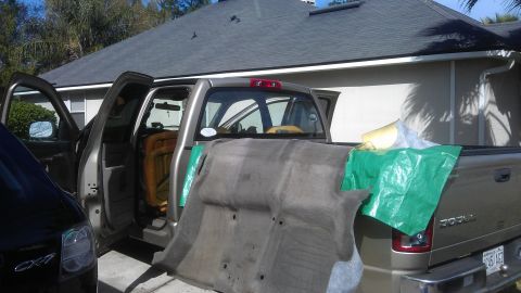 1994 Ford Bronco - A silver pickup truck is shown with its doors open and interior carpet removed, parked next to another vehicle.