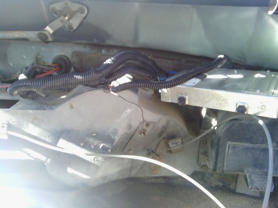 Engine bay wiring and computer module. Some text visible on metal casing