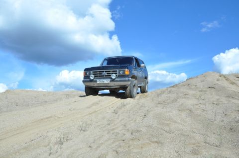 1987 Ford Bronco - This 1987 Ford Bronco navigates a sandy incline under a bright blue sky.